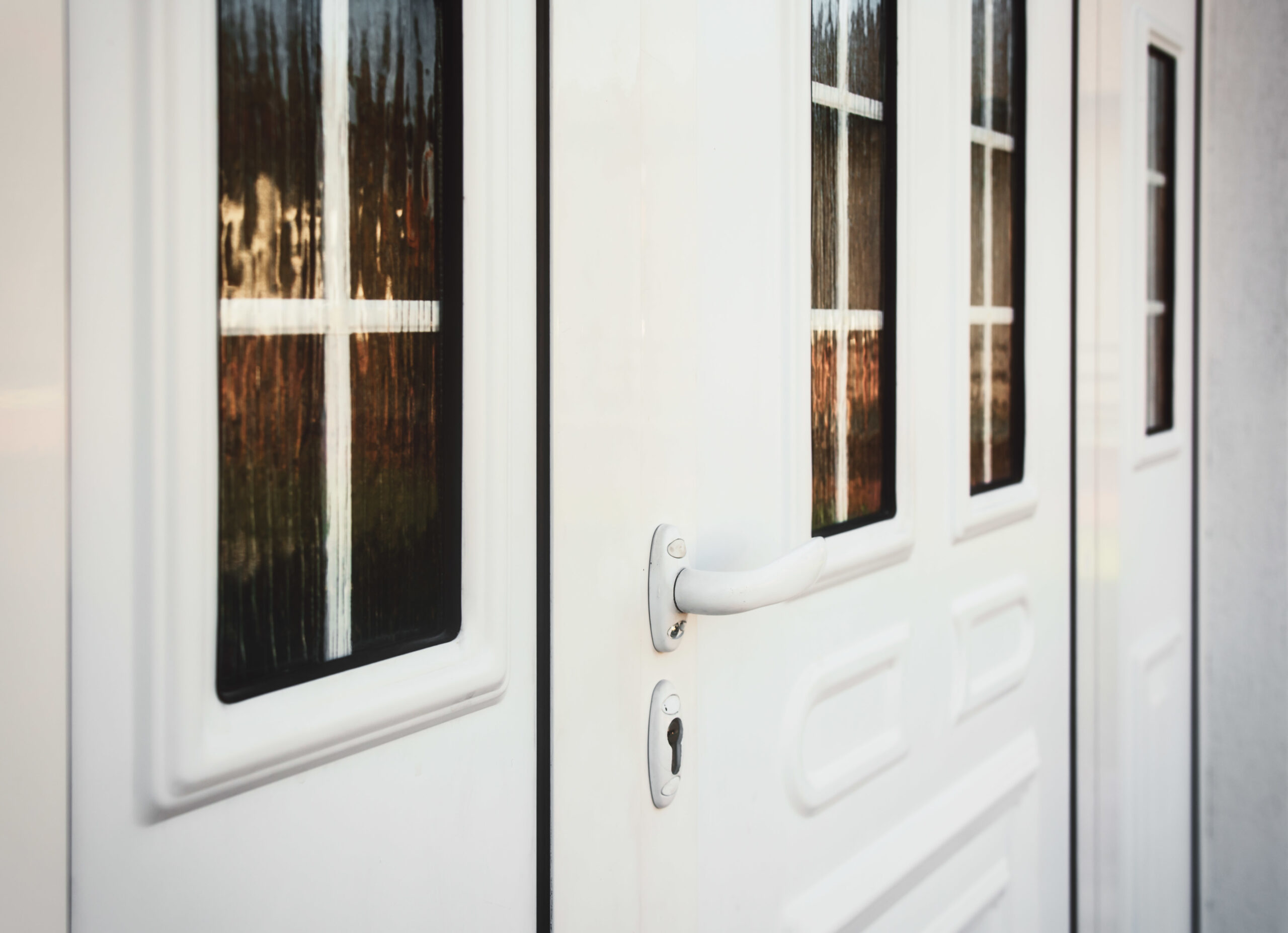 Up-close picture of white door with a lever knob to the front entrance of a home.