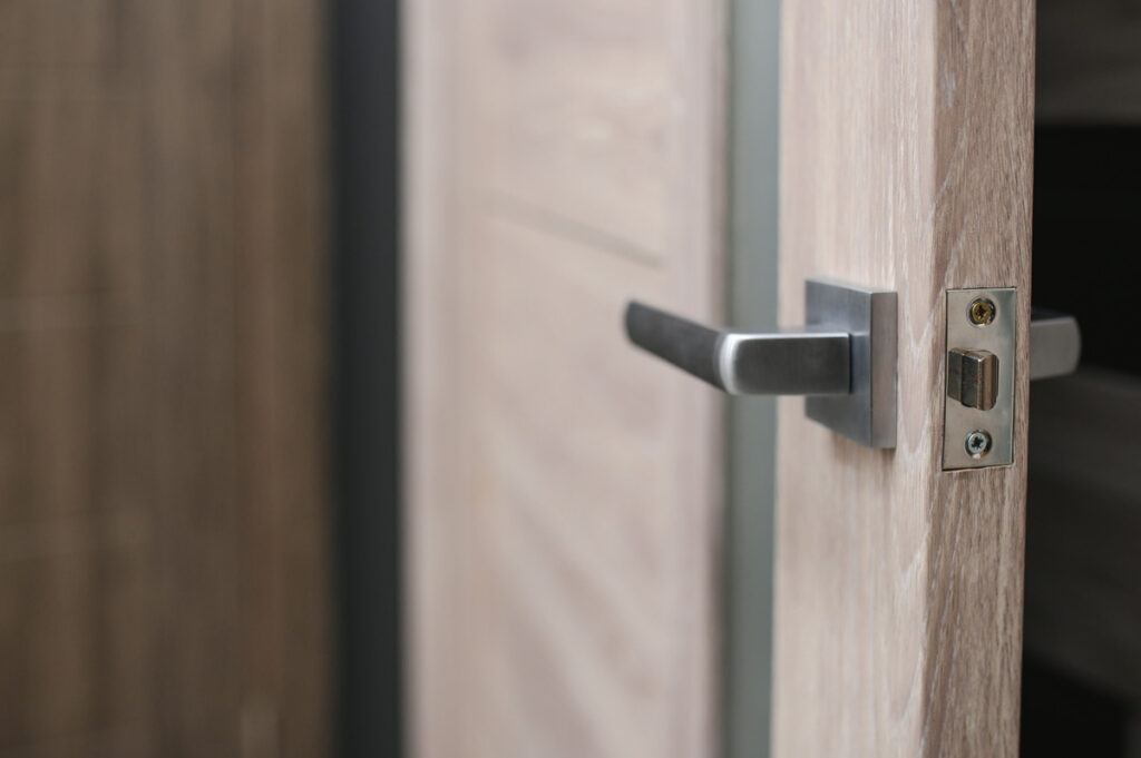 A silver handle on a light wooden door.