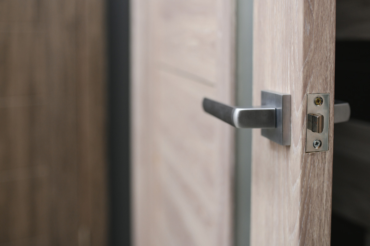 A silver handle on a light wooden door.